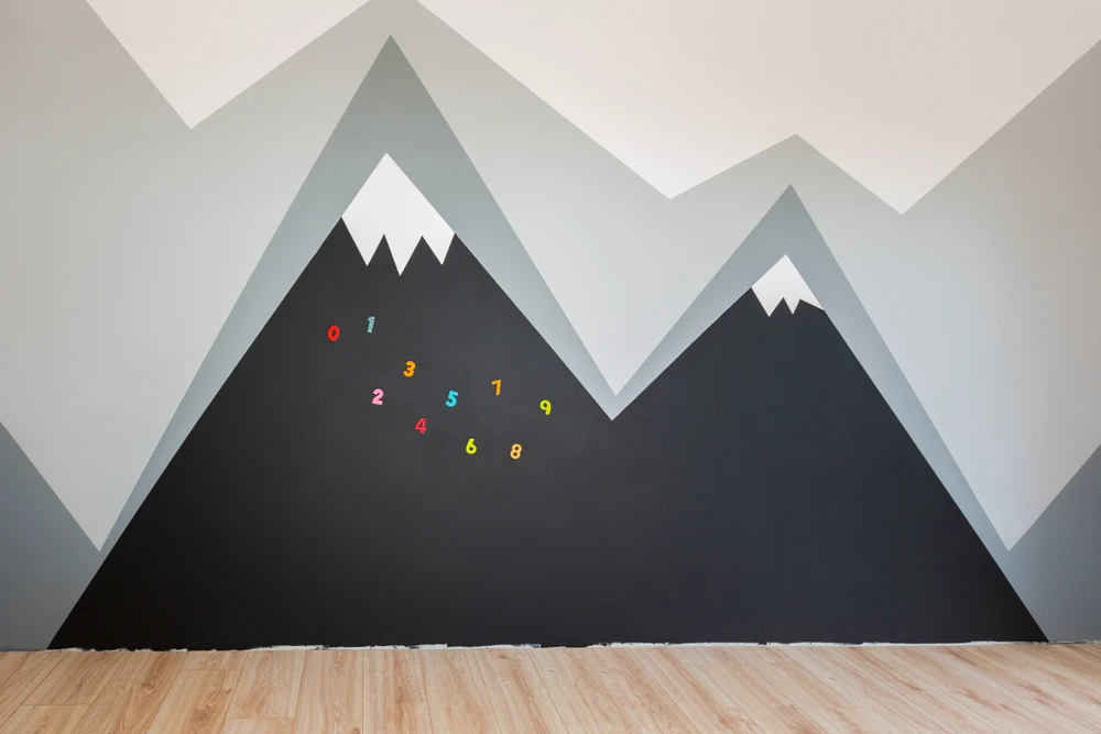 Mur intérieur avec fresque murale géométrique représentant des montagnes stylisées en dégradé de gris et blanc