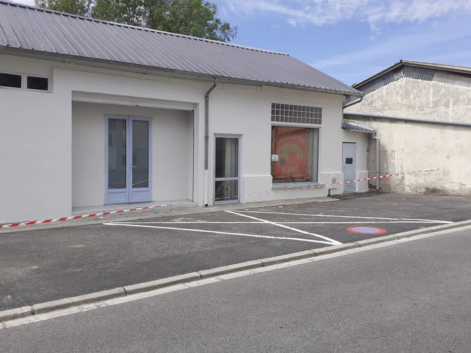 Scène extérieure d'un chantier de rénovation de bâtiment commercial avec façade blanche fraîchement enduite, toiture métallique ondulée