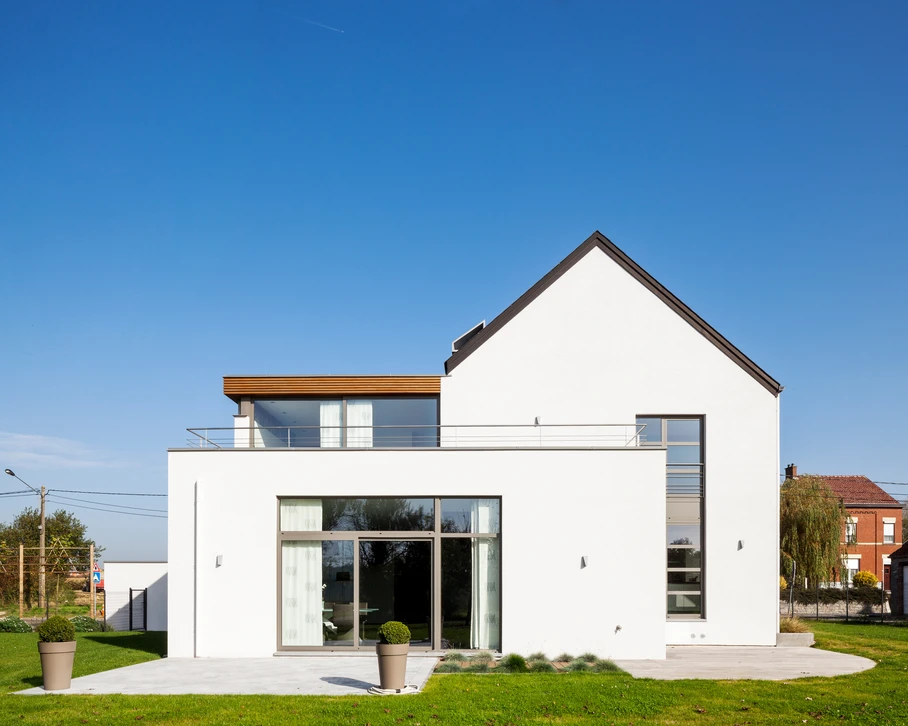 Homme peignant un mur extérieur avec un rouleau à manche télescopique, appliquant de la peinture turquoise sur une surface beige