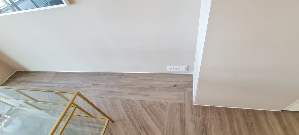 Travailleur portant des gants de protection blancs avec revêtement orange antidérapant manipule une scie à métaux pour découper une planche en bois massif