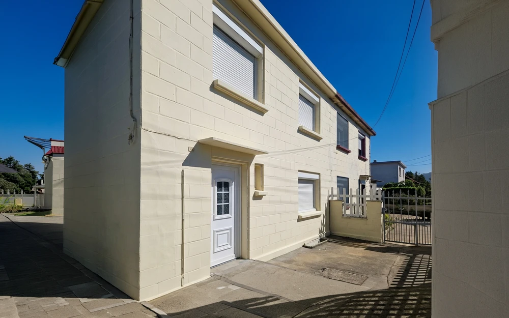 Intérieur résidentiel en cours de rénovation avec échelle de peintre positionnée devant fenêtres à persiennes